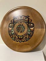 Front view of round wooden tray with Indigenous painted animal design in multiple colors on cedar wood.