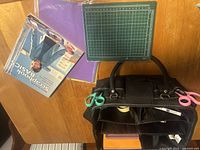 Photo showing scrapbooking book, cutting mat, and part of organizer bag with scissors attached