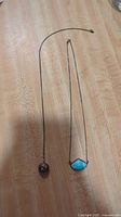 Two vintage necklaces laid out on a wooden surface showing overall length and pendants