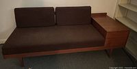 Front view of teak sofa bed loveseat with brown upholstery and attached side table.