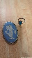 Photo of Wedgwood cameo brooch or pendant and sterling ring with blue stone on wood surface