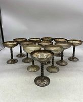 Front view of twelve silver plated chalices arranged in a triangular layout showing the full set.