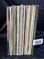 Photo showing the side view of 37 assorted vinyl records stacked together