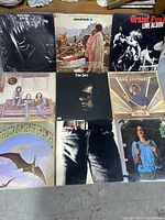 Overhead shot of 9 vinyl record albums showing Woodstock 3-album set, Grand Funk, Elton John, Rod Stewart, The Flock, Mud Slide Slim and others