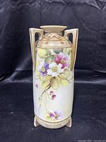 Front view of the antique vase with floral handpainted decoration, handles, and geometric border detail