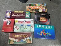Wide view of all nine games showing titles and box art of Cat-opoly, Pictionary, Scattergories, Monopoly, Guesstures, Rummy-o, Quixo, and more