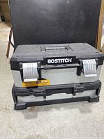 Front view of Bostitch metal tool box, showing brand name on the top flip lid and metal latches.