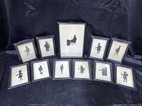 Full set of 11 framed silhouette character pictures, black frames on black background.