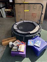 Fitness trampoline with handlebar, two stepper blocks, wooden block, small fitness roller, and workout DVDs grouped together
