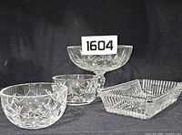 Four Waterford crystal pieces: two small bowls, one pedestal bowl, one rectangular dish, arranged on dark fabric background with lot number 1604.
