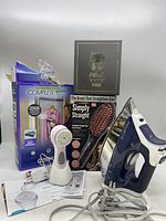 Rowenta iron with steamer door pad, facial brush, Simply Straight hair brush, and Pitbull Skull Shaver box