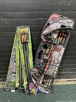 Junior compound bow with three packs of arrows in original packaging displayed together.