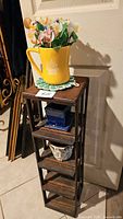 Wooden shelf stand with planters and acrylic flowers placed in the yellow pitcher on top, visible all four levels with different ceramic planters on the shelves