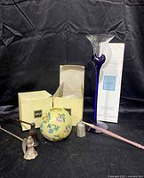 Full lot showing two ball candles in boxes, blue glass diffuser bottle with diffuser reeds, and three metal candle snuffers of different designs.