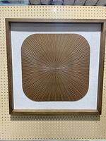 Front view of the modern wooden wall art piece showing the framed rectangular artwork on white background with radiating carved lines forming a rounded square pattern.