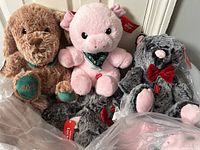 Three plush animals visible: brown dog with 2024 embroidery, pink pig with green bandana, gray mouse with red bow tie.