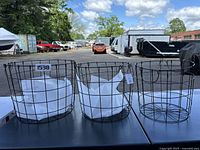 Set of three black wire metal baskets in different sizes on a table outdoors, showing entire group