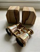 Photo showing three items: a pair of sandstone bookends with natural color bands and a pair of opera binoculars featuring mother of pearl and brass construction.