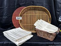 Vintage oval rattan tray, round red rattan placemat, cream tablecloth, and cream napkins in wicker basket