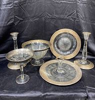 Full set of 1920s ornate glass serving pieces with detailed sterling silver trim on black background showing all items together.