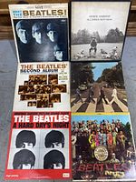 Six album covers of Beatles LPs and George Harrison box set laid out
