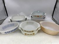 Front view of all seven vintage baking dishes arranged in two rows showing various sizes and patterns.