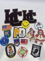 Top view showing all vintage patches including letters H and E, smiley face, red-haired dolls, flags, and military patches