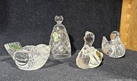 Front view of four Waterford crystal figurines on black background showing fish-shaped bird, bell, swan, and smaller bird with Waterford stickers visible