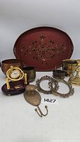 Photo showing all items in the lot including wood tray, clock, metal decor items, ornate frames, brass and copper containers