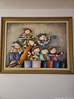 Framed print showing six musicians in colorful striped attire playing different instruments, set within a decorative gold frame.