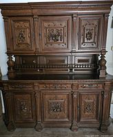 Front view of large antique wooden hutch showing upper and lower cabinets with ornate carved panels and turned columns