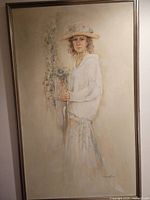 A full view of the large watercolor painting showing a woman wearing a hat and holding flowers, framed.