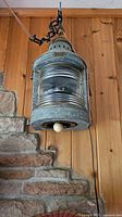 Front and side views of working maritime lantern lamp hanging on wall with wooden and stone background.