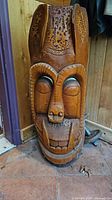 Front view of Polynesian wooden carved mask showing detailed facial features and wood texture.