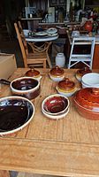 Top angle photo of all stoneware cookware on wooden table including lidded pots, round bowls, and casserole dishes