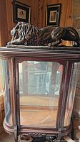 Front view of china cabinet with reclining lion sculpture on top, showing overall size and appearance