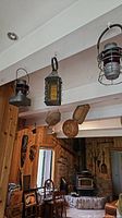 Wide view of all three vintage lanterns hanging from a beam, showing their condition and surroundings in a rustic interior.