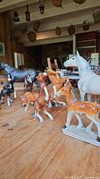 Overview of assorted horse figurines on a wooden table showing various sizes and colors.