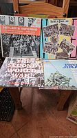 Photo showing four World War II themed vinyl records including 'Hitler's Inferno', 'Victory in Europe 1945', 'The Second World War', and 'Iwo Jima' on a wooden chair