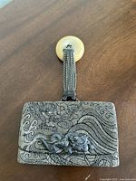 Front view of antique Japanese Meiji Era tobacco pouch showing embossed dragon and wave design with metal dragon embellishment and beaded handle.