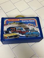 Closed blue Matchbox carry case with handle and colorful car illustrations on the top.