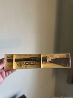 Photo of the wooden Apache Frontier Rifle toy replica in original yellow box with printed text and graphics.