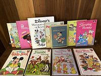 Photo showing all 10 vintage hardcover Disney children's books arranged on a wooden surface, displaying colorful covers with classic Disney illustrations.