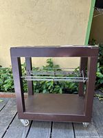 Front view of vintage mid century small rolling cart showing metal frame, bottom shelf, and wire rack in the middle section.