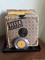 Photo showing front view of lot of vintage 78 RPM records standing together in sleeves including Decca Records and Gold Tone records