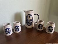 Photo showing vintage sandstone pitcher and four matching cups all decorated with blue rooster and weather vane design.