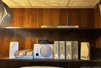 Wide view of the Yamaha YST-MSW10 subwoofer, speakers, and the binders on a wooden shelf