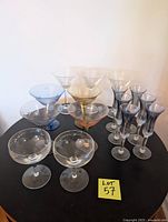 Full lot of 15 assorted glass stemware pieces displayed on black table.