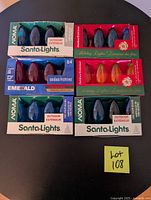 Five boxes of assorted outdoor incandescent Christmas light bulbs including blue, red, and multicoloured bulbs from NOMA and Holiday Lights brands arranged on a black surface.
