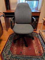 Front view of grey fabric office chair showing seat, backrest, armrests, and caster base.